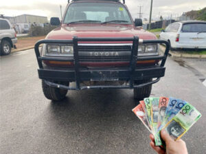 Front view of red Toyota 4WD with bull bar and Australian banknotes fanned in foreground